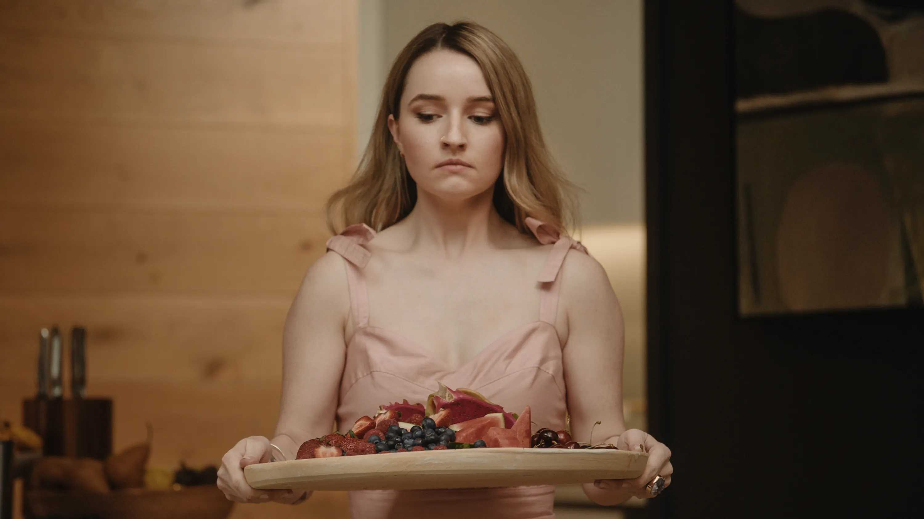 Kaitlyn Dever holding a plate of fruit in apple cider vinegar