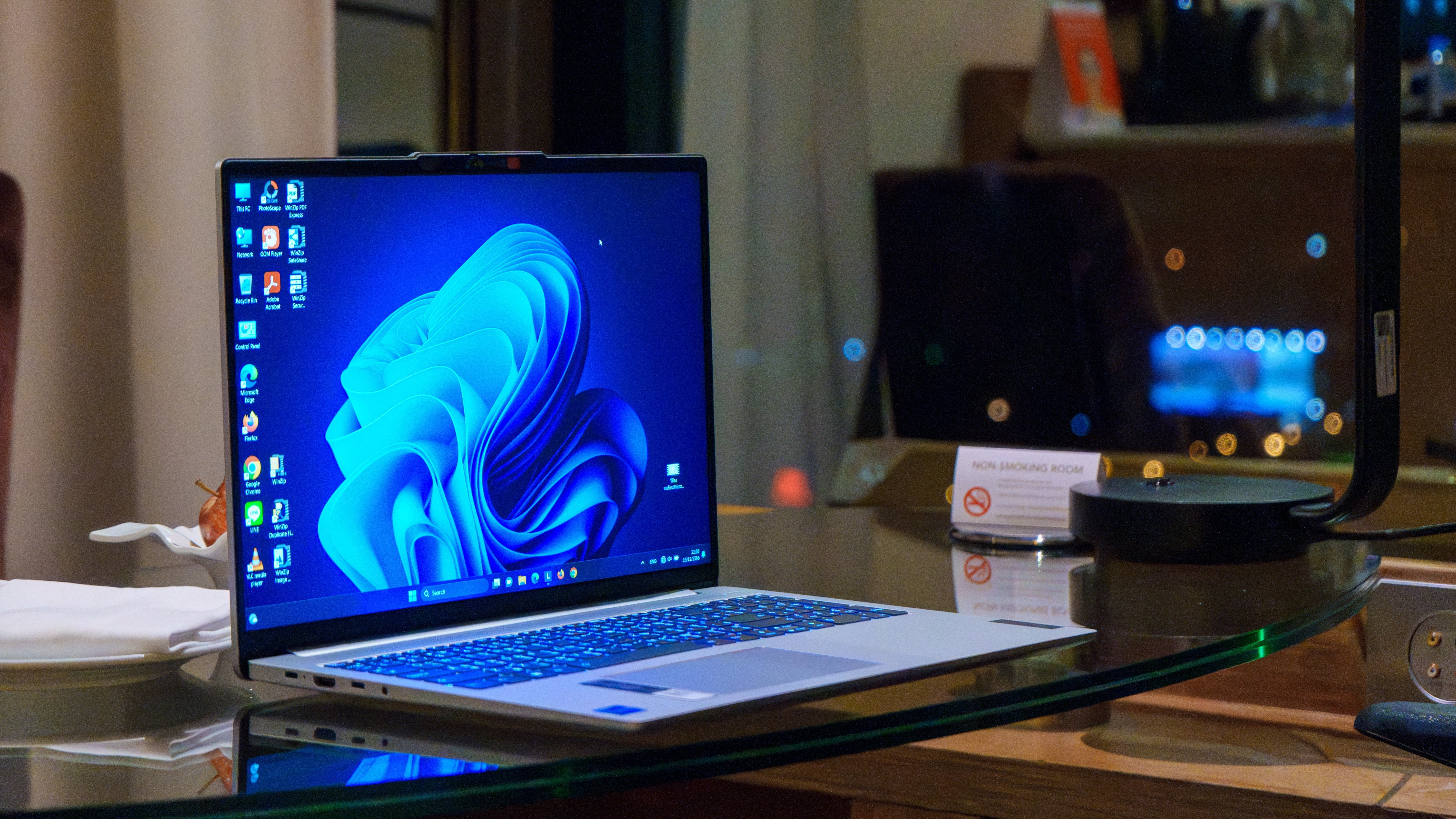 A laptop with the Windows 11 desktop on the screen, glowing while you're at a desk