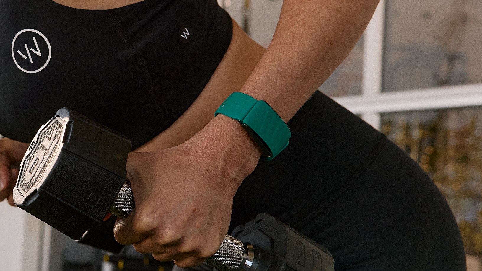 Woman who lifts dumbbell while she wears Whoop -Unit on the wrist