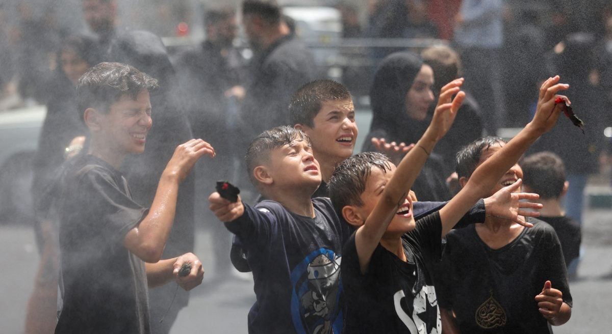 Children are cooled under water sprinklers when attending a ceremony to mark Ashura in Tehran, Iran, July 6, 2025. - Reuters