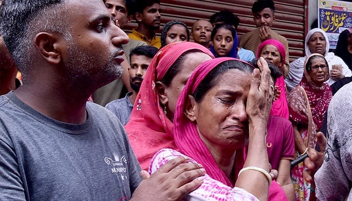 Grief-affected family members break down in tears at the tragic place for a crashed residential building in Bagdadi, Lyari. - App/file