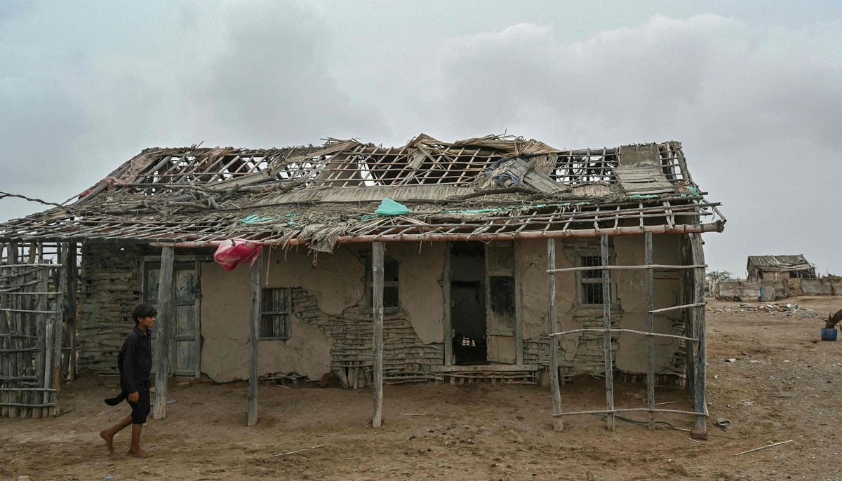 A boy goes past an abandoned house in one of the villages of Kharo Chan Town, in Indus Delta on June 25, 2025. - AFP