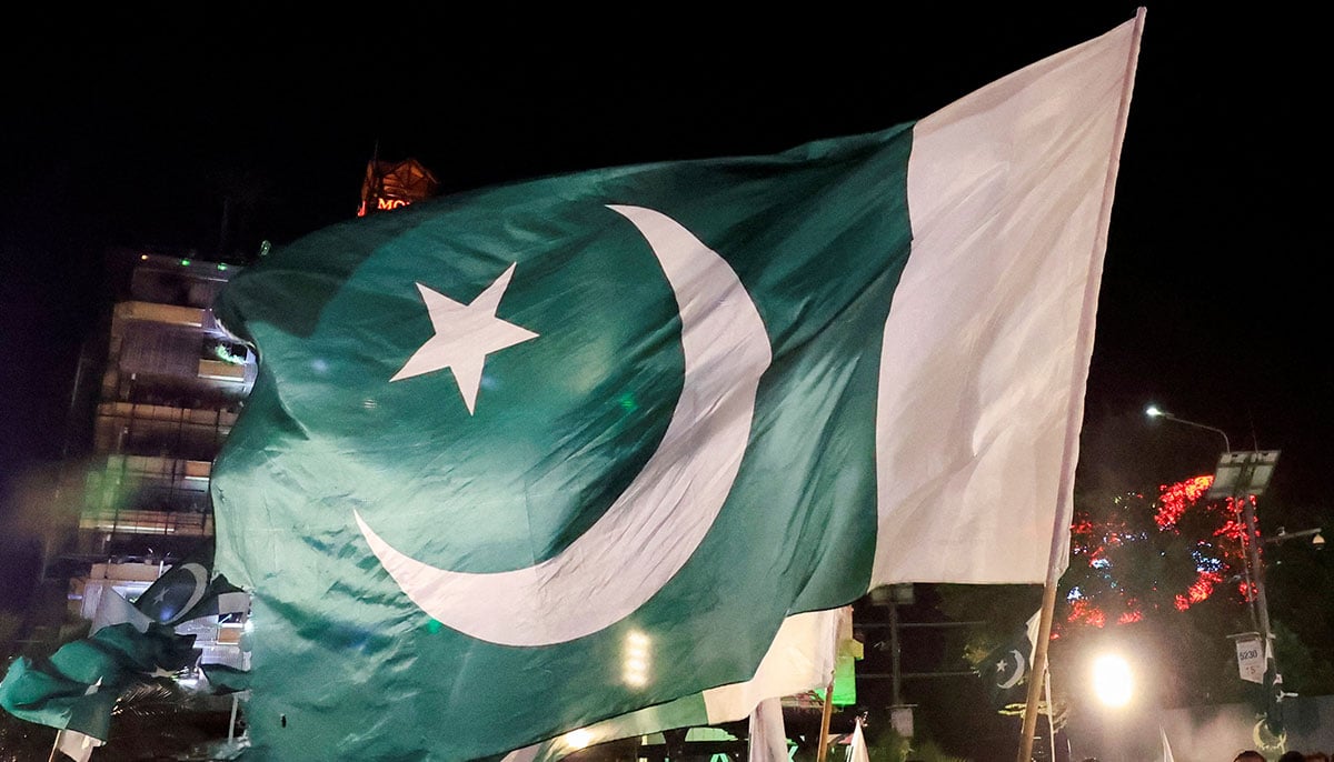 People waving national flags while gathering on the threshold for the independence day in Lahore on August 13, 2025. - Reuters