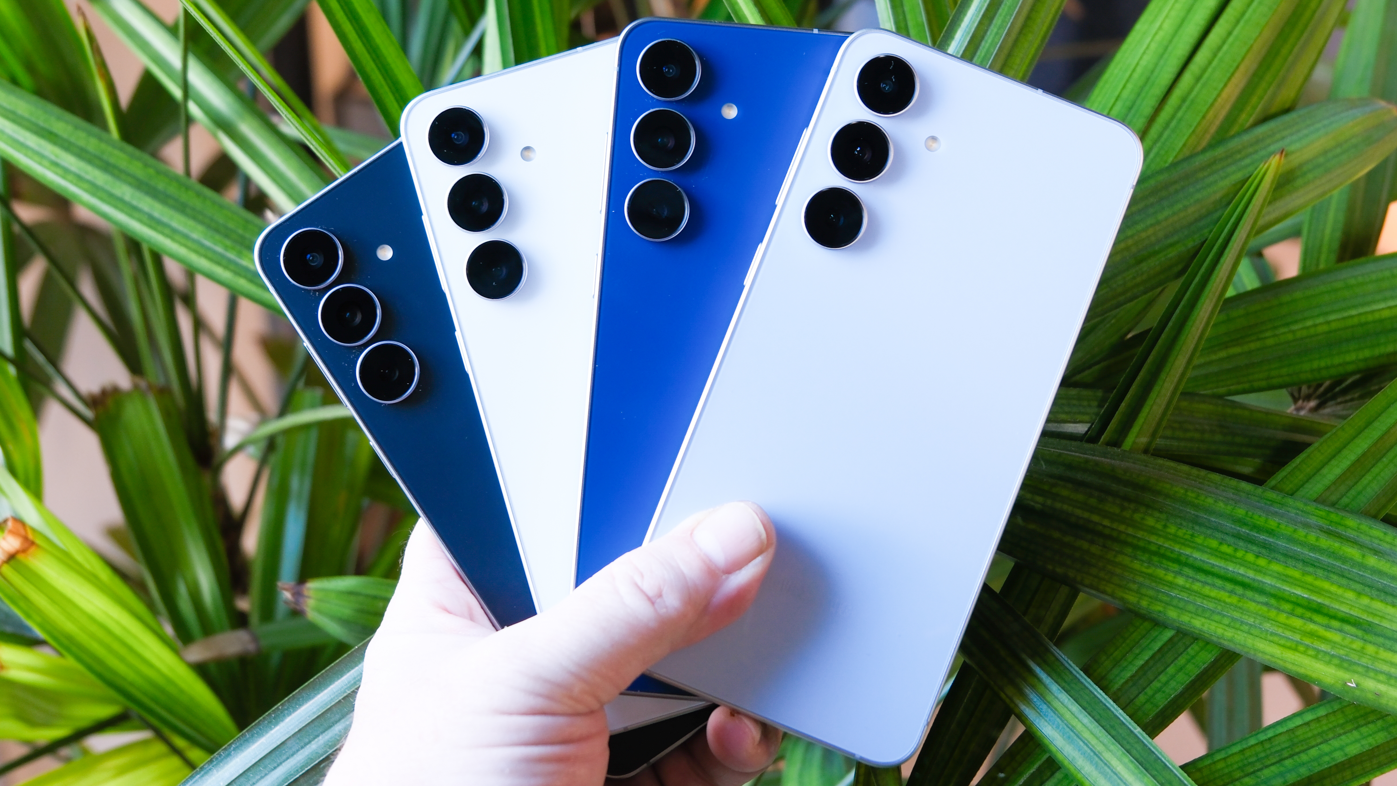 Samsung Galaxy S25 Fe in the hand with long green leaves on the back