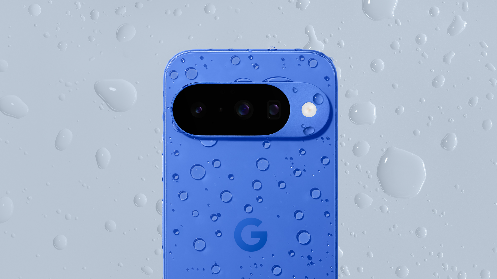 An Indigo Blue Version of Google Pixel 10 phone covered with water drops on a gray background