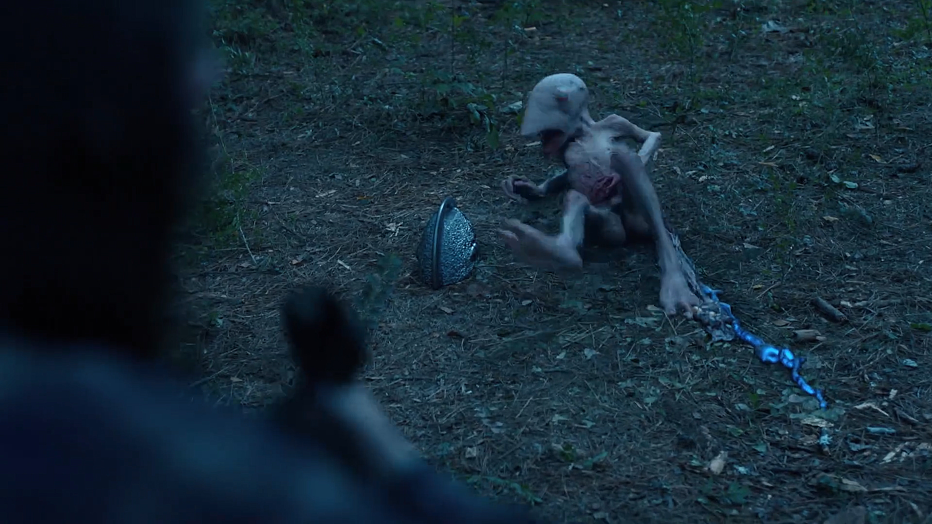 A stranger lying severely wounded on the forest floor with a silver case sitting next to it in peacekeeper season 2 section 4