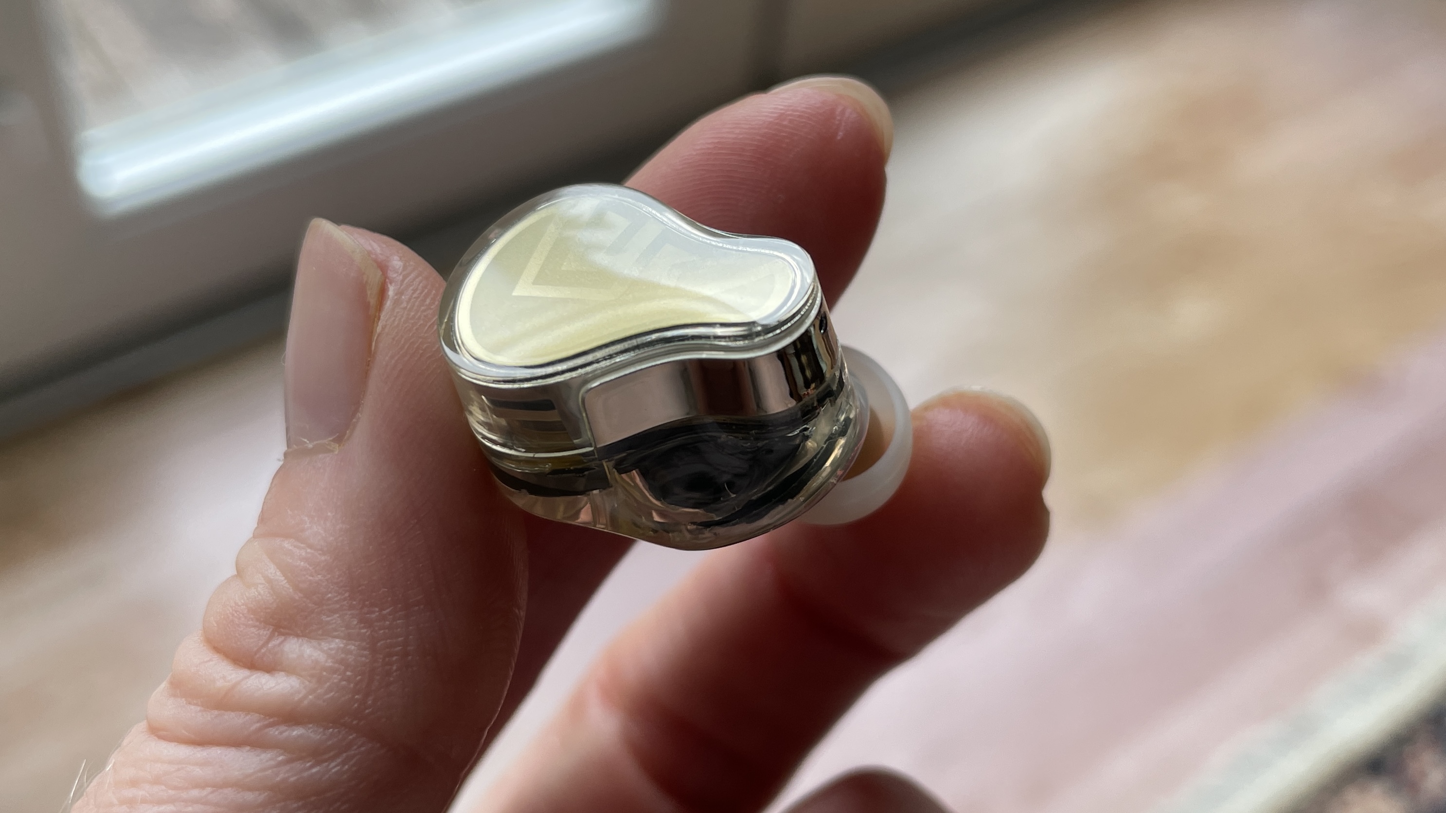 Soundpeats H3 earplugs and case held in one hand in a living room