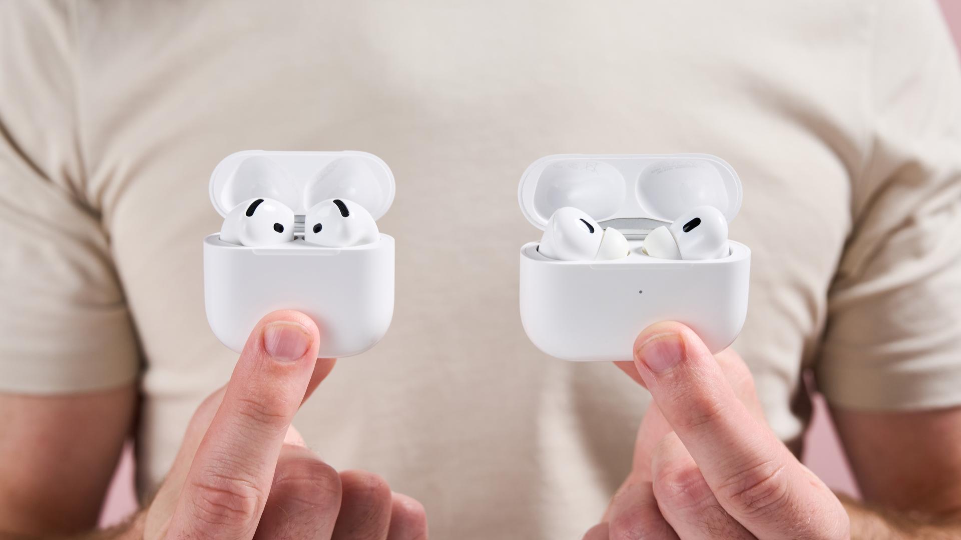 The open cases for AirPods Pro 2 and AirPods 4 held next to each other showing the top of the earbuds that stick out