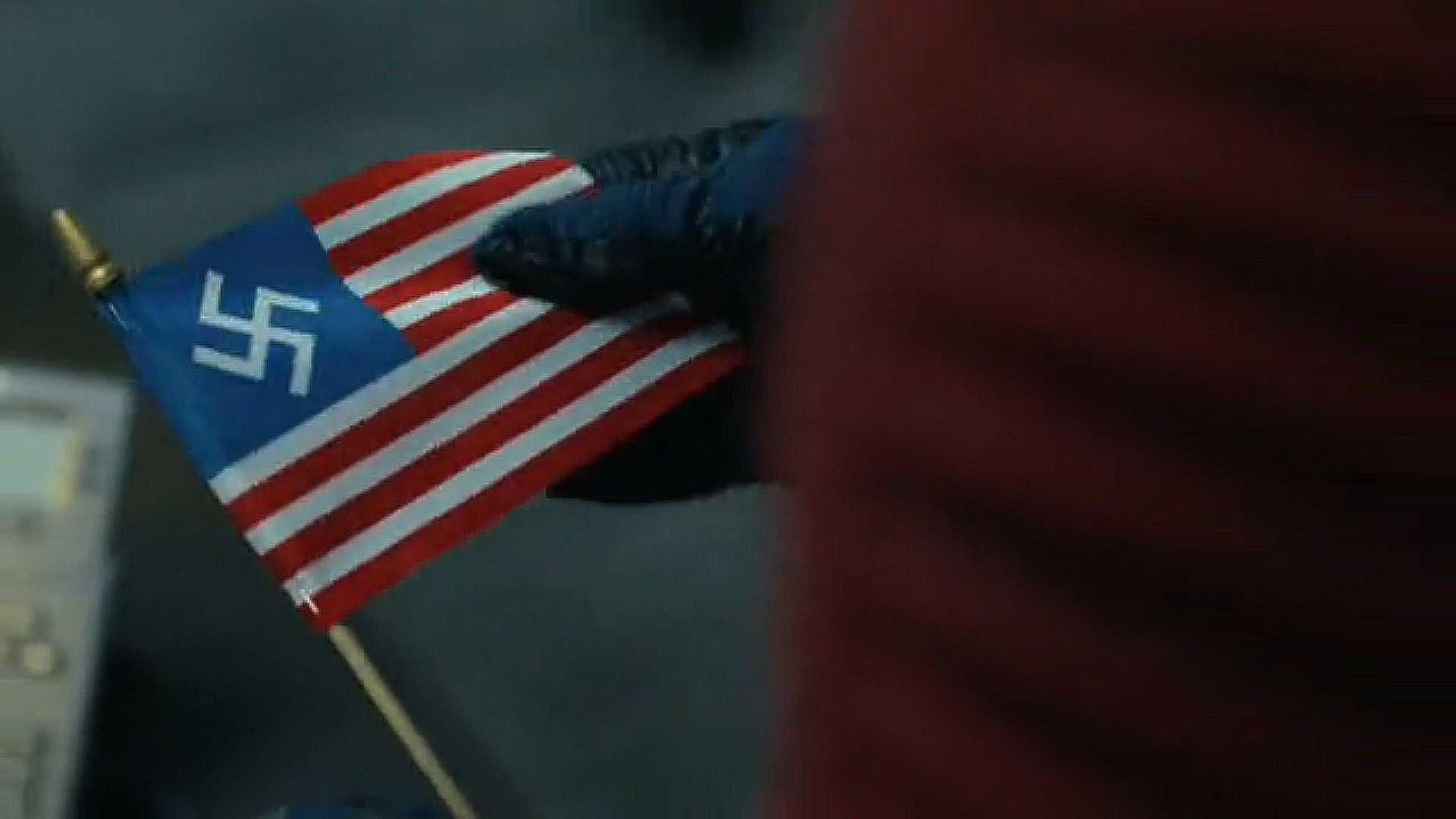 A close -up of Chris Smith holding an American Nazi flag in Peacemaker season 2 section 6