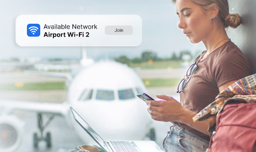 A woman sitting at the airport using a laptop and a phone connected to Wi-Fi