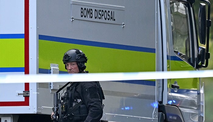 An armed police officer passes a bomb disposal van outside Heaton Park Hebrew Church Synagogue in Crumpsall, North Manchester, on October 2, 2025, after an attack on the synagogue. - AFP