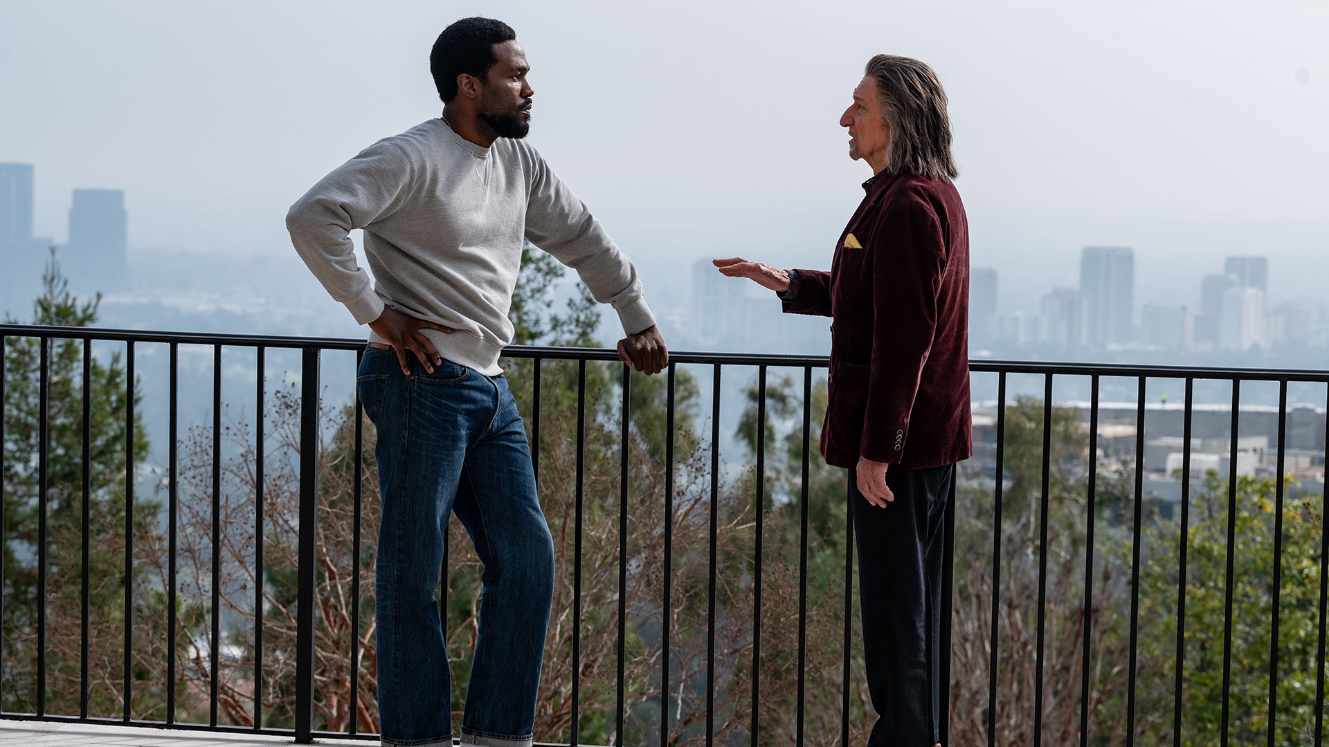 Simon Williams and Trevor Slattery chatting next to some metal fence in Wonder Man