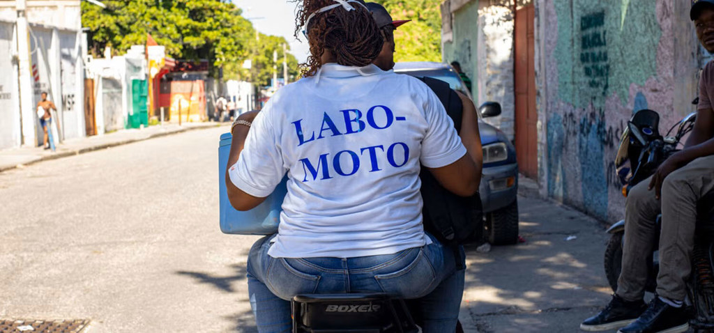 A 'Labo Moto' health worker is traveling by motorcycle to visit a patient.