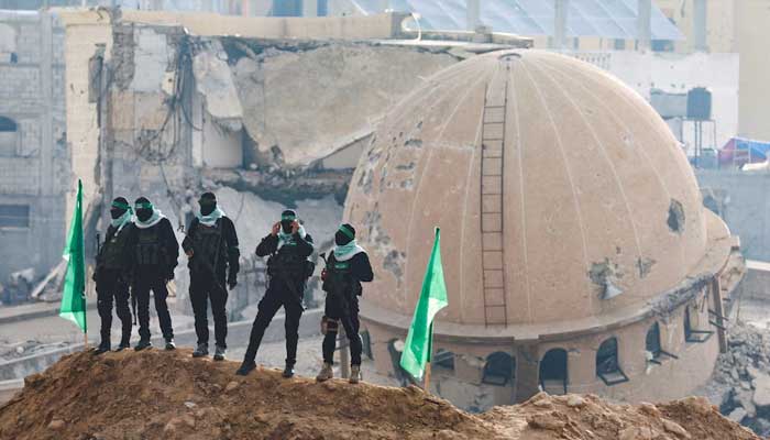 Hamas Fighters stand guard during a handover of deceased hostages in the southern gaza strip, February 2025. - Reuters