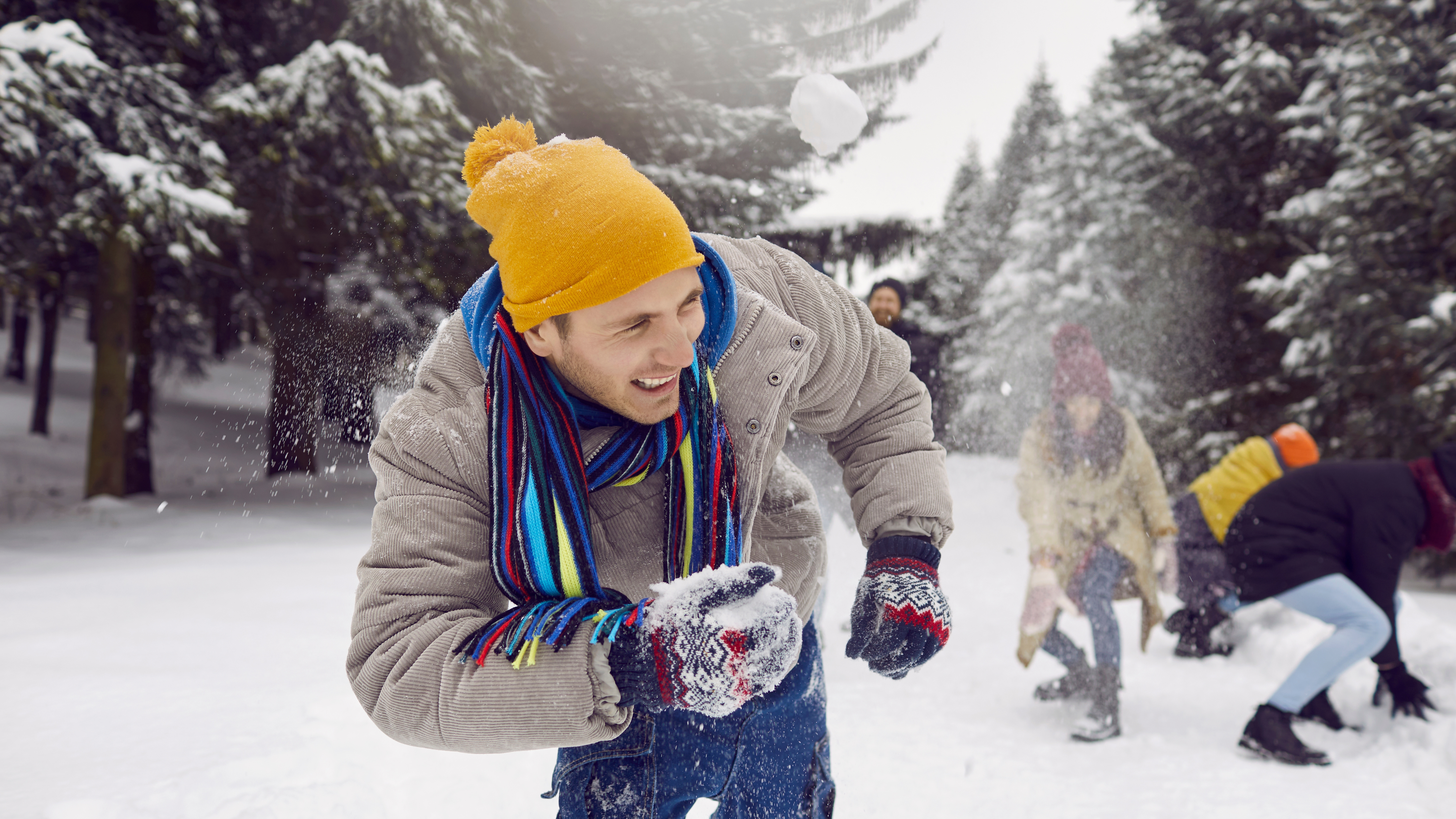 A man outside in a snow fight with friends