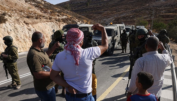 Palestinian farmers argue with Israeli security forces after their harvest was disrupted by Israeli settlers and halted by Israeli security forces in the village of Sa'ir, near the Israeli-occupied West Bank city of Hebron, on October 23, 2025. — AFP