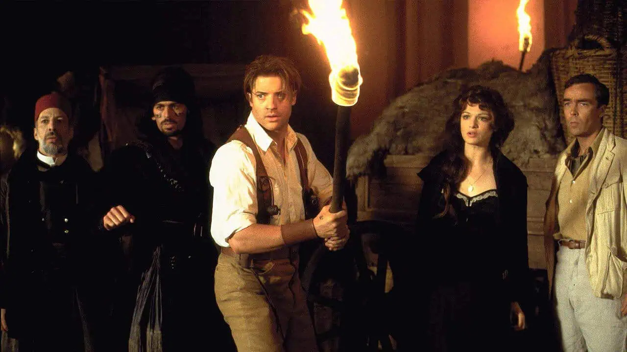 A group of treasure hunters hold fire torches in a tomb in The Mummy