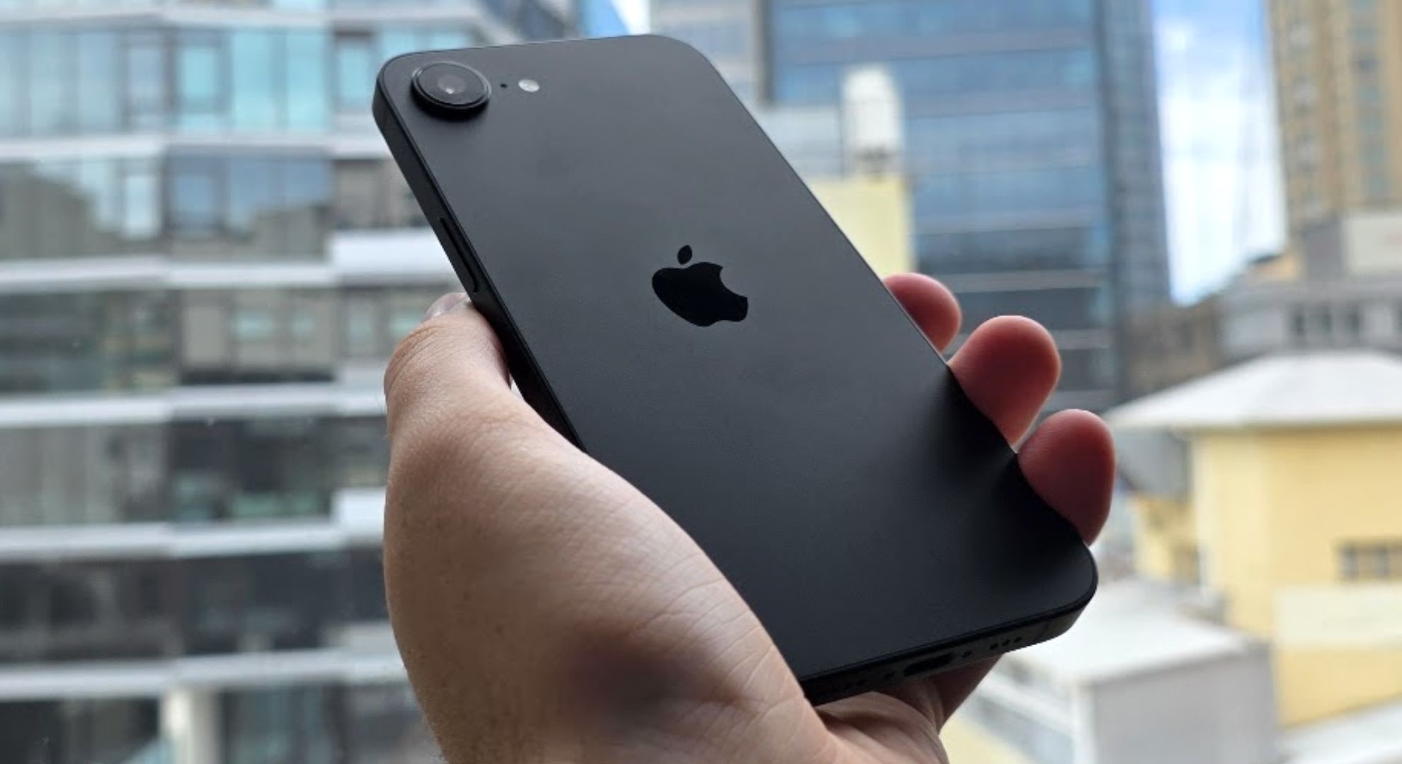 Apple iPhone 16e held at an angle against a window