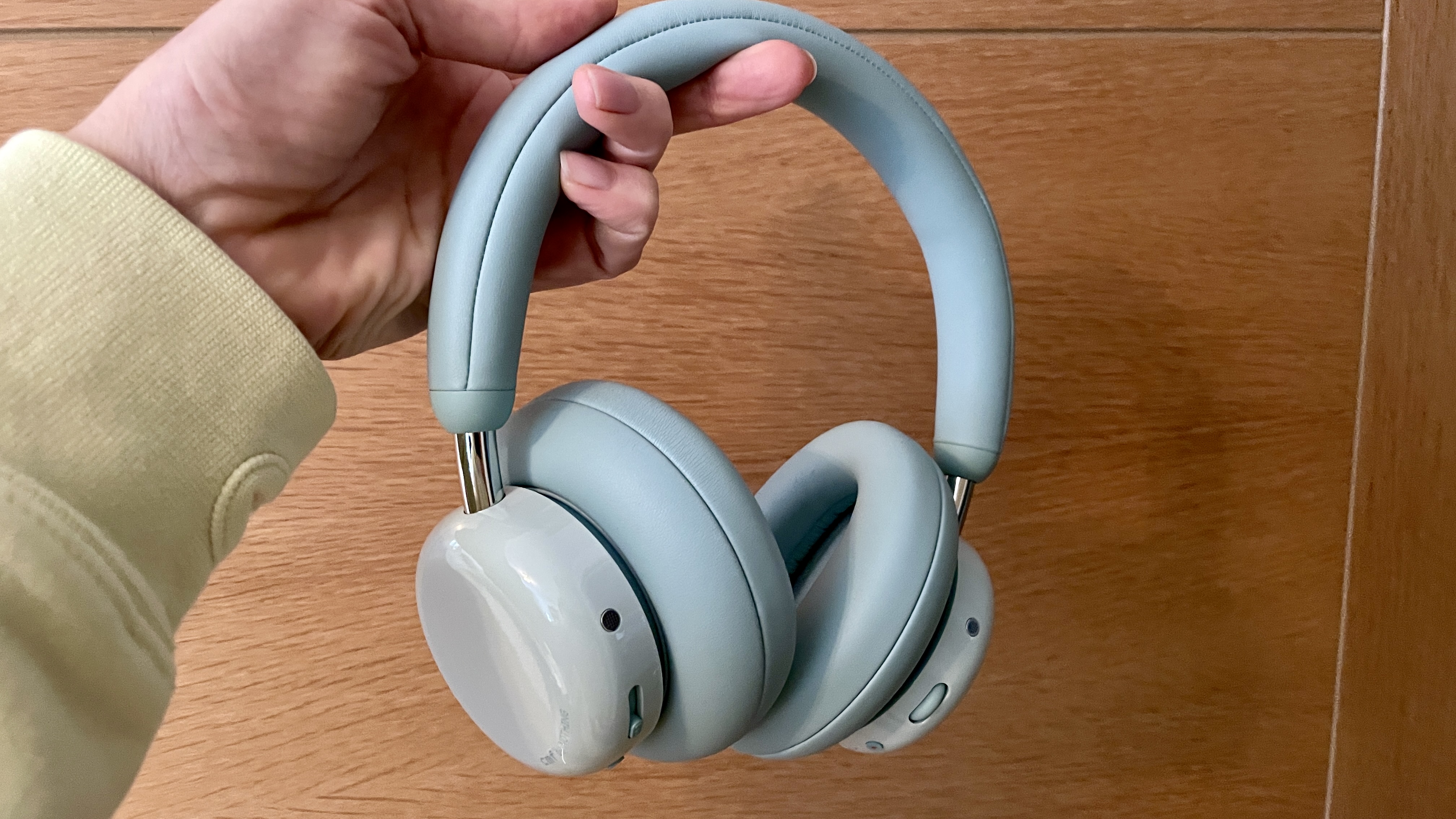 CMF Headphone Pro in pistachio green held in hand or hung on a barbell, is pushed up by a carved frog
