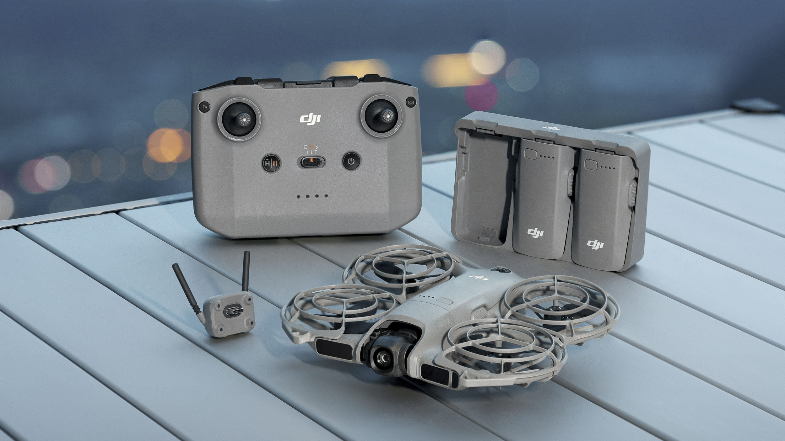 DJI Neo 2 selfie drone on a table next to controller, battery hub and antenna