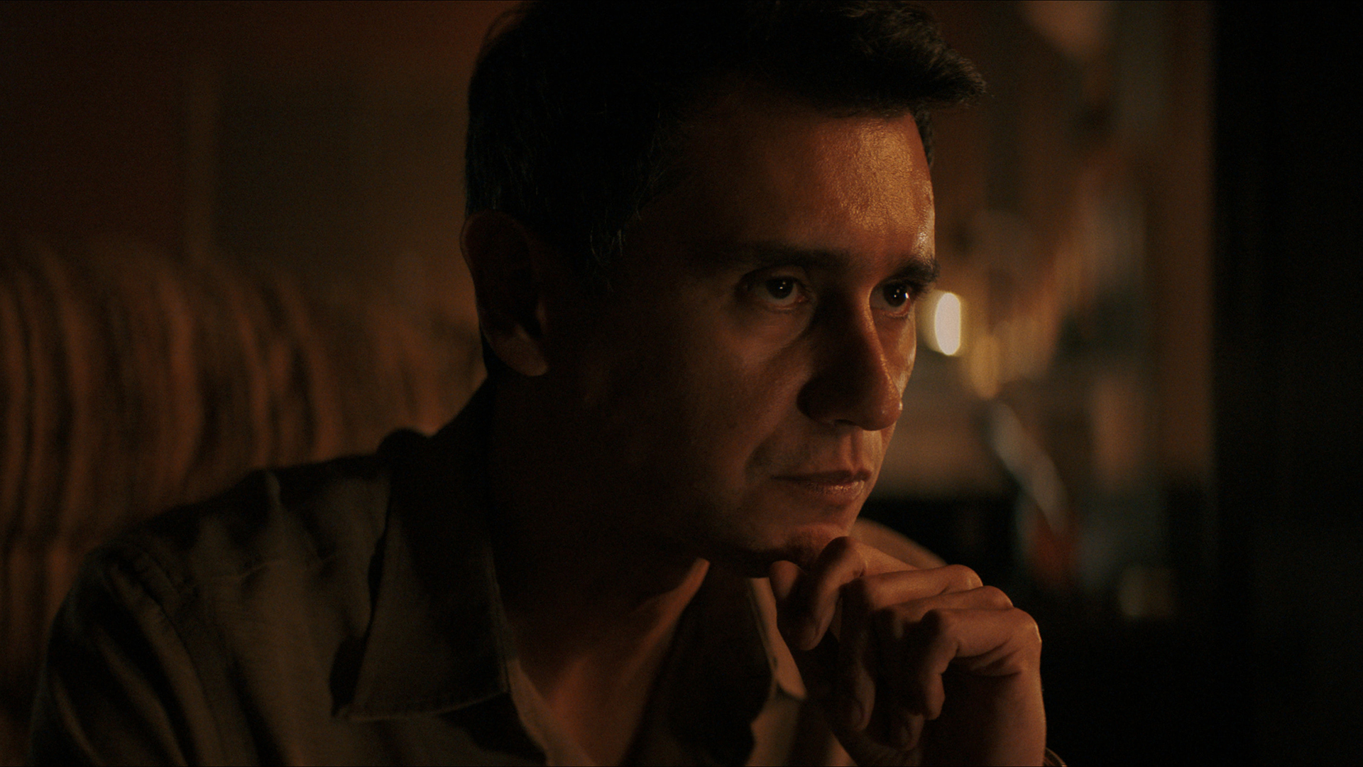 Manusos rested his chin on his left hand in Pluribus episode 4