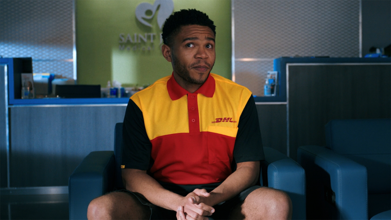 A screenshot of a DHL delivery driver looking up and to the right as he sits down in Pluribus episode 3