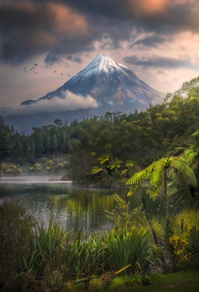 A snowy mountain with a tropical lake in the foreground