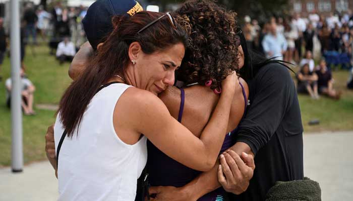 People embrace as they visit a makeshift memorial following the attack on a Jewish holiday at Sydney's Bondi Beach in Sydney, Australia on December 15, 2025. — Reuters