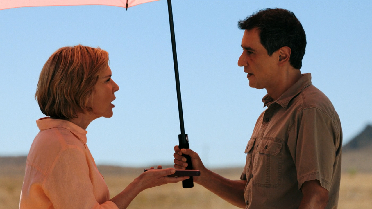Carol and Manousos argue under an umbrella in Pluribus episode 9
