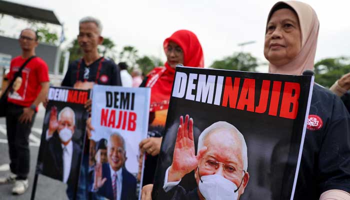 Supporters of former Malaysian Prime Minister Najib Razak hold banners with his portrait outside the Palace of Justice in Putrajaya, Malaysia on December 26, 2025. — Reuters