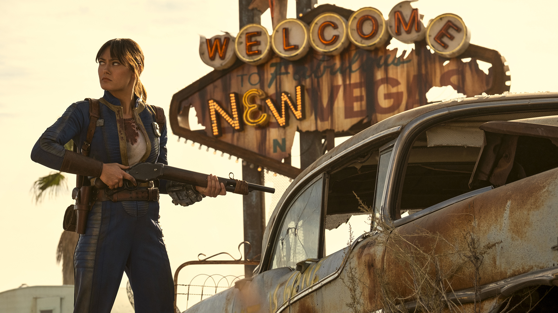 Lucy MacLean holds a shotgun next to a rusty car near New Vegas in Fallout Season 2