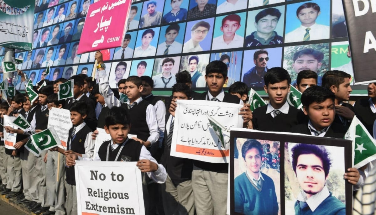 In this photograph, Pakistani students gather near a board displaying images of the victims of the APS attack. — AFP/file