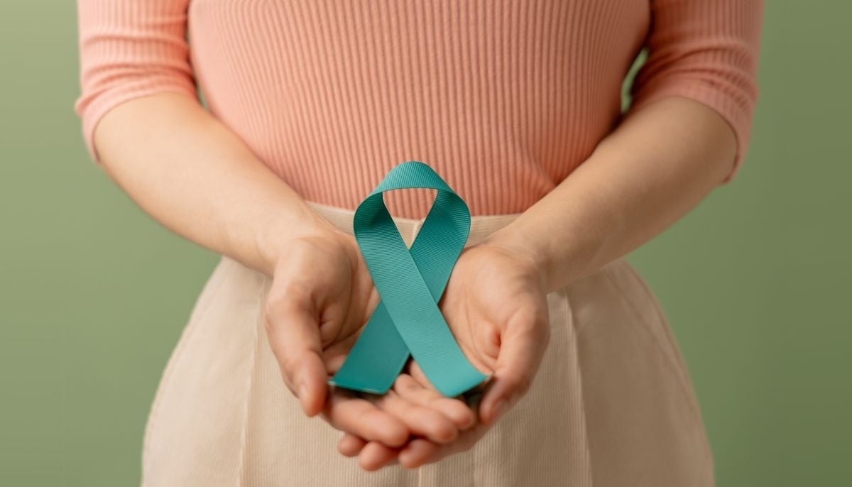 A representative image of a woman holding a teal ribbon indicating the symbol of cervical cancer awareness. — Canva