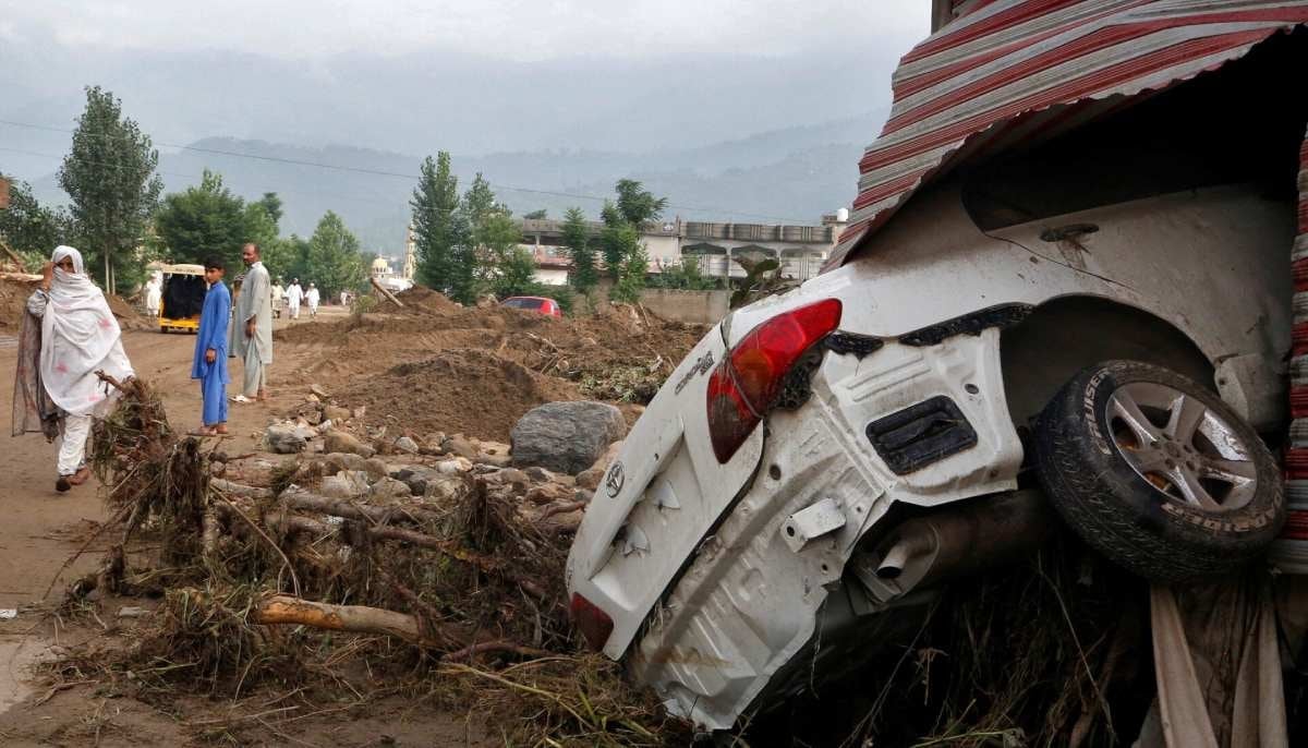 A woman walks past a damaged vehicle after heavy rain and flooding in Buner district of Khyber Pakhtunkhwa on August 16, 2025. — Reuters