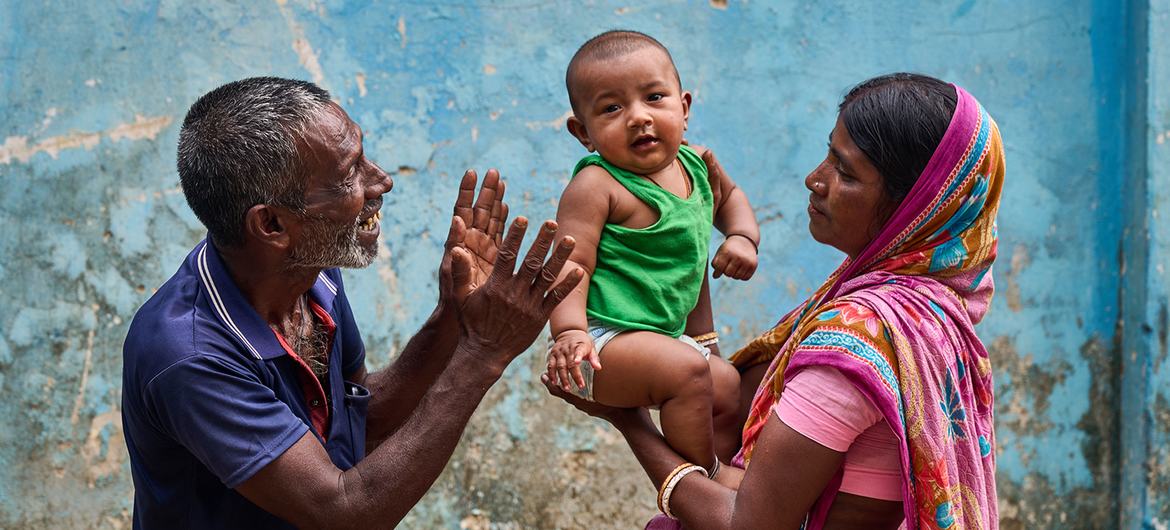 A baby is held by its mother and entertained by its grandfather at a community clinic in northern Bangladesh. 