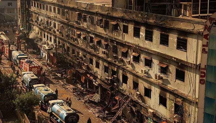 Fire department personnel walk past the scene after a massive fire broke out at the Gul Plaza shopping mall in Karachi on January 20, 2026. — Reuters