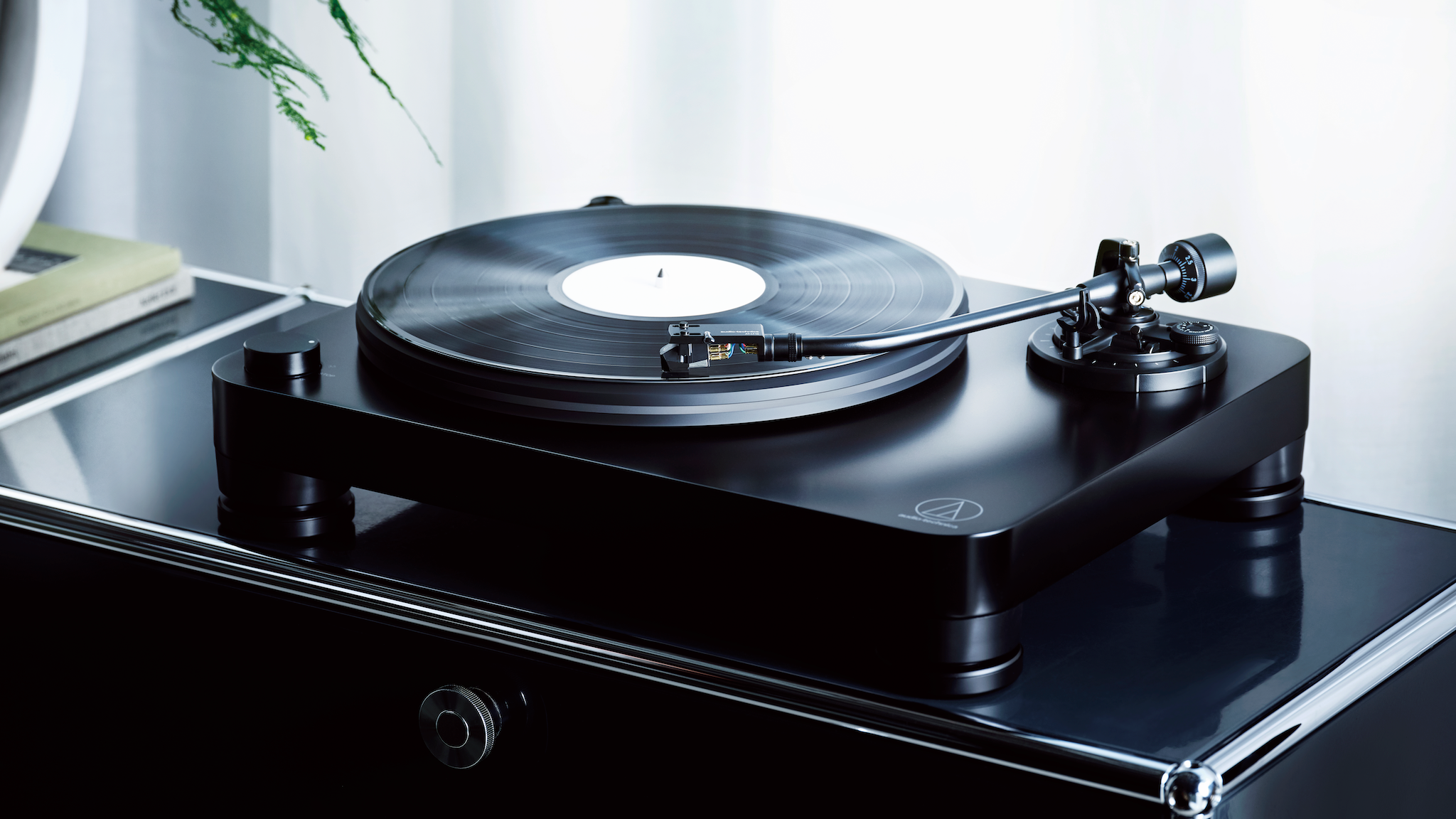 Audio-Technica AT-LP7X turntable on a black amplifier near a window