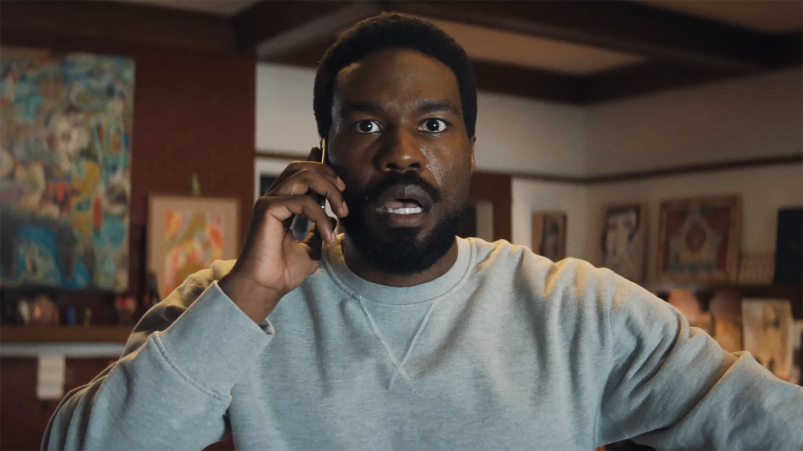 Simon Williams looks shocked as he listens to someone during a cell phone call in Marvel's Wonder Man