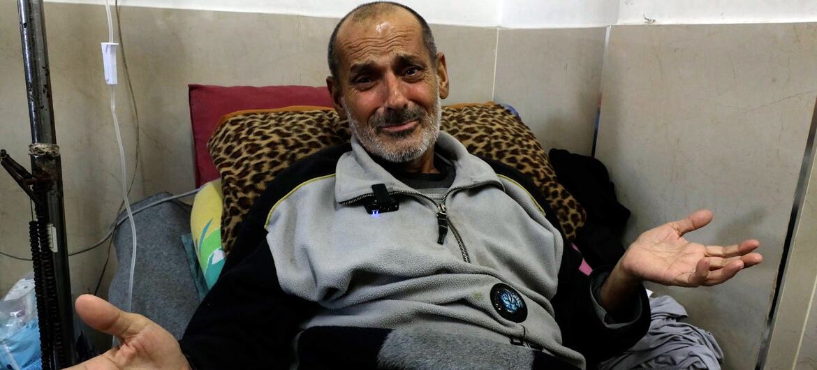 Mundhir Abu Foul, a cancer patient in Gaza, sits on a hospital bed with his hands open and appears to be speaking or gesturing.