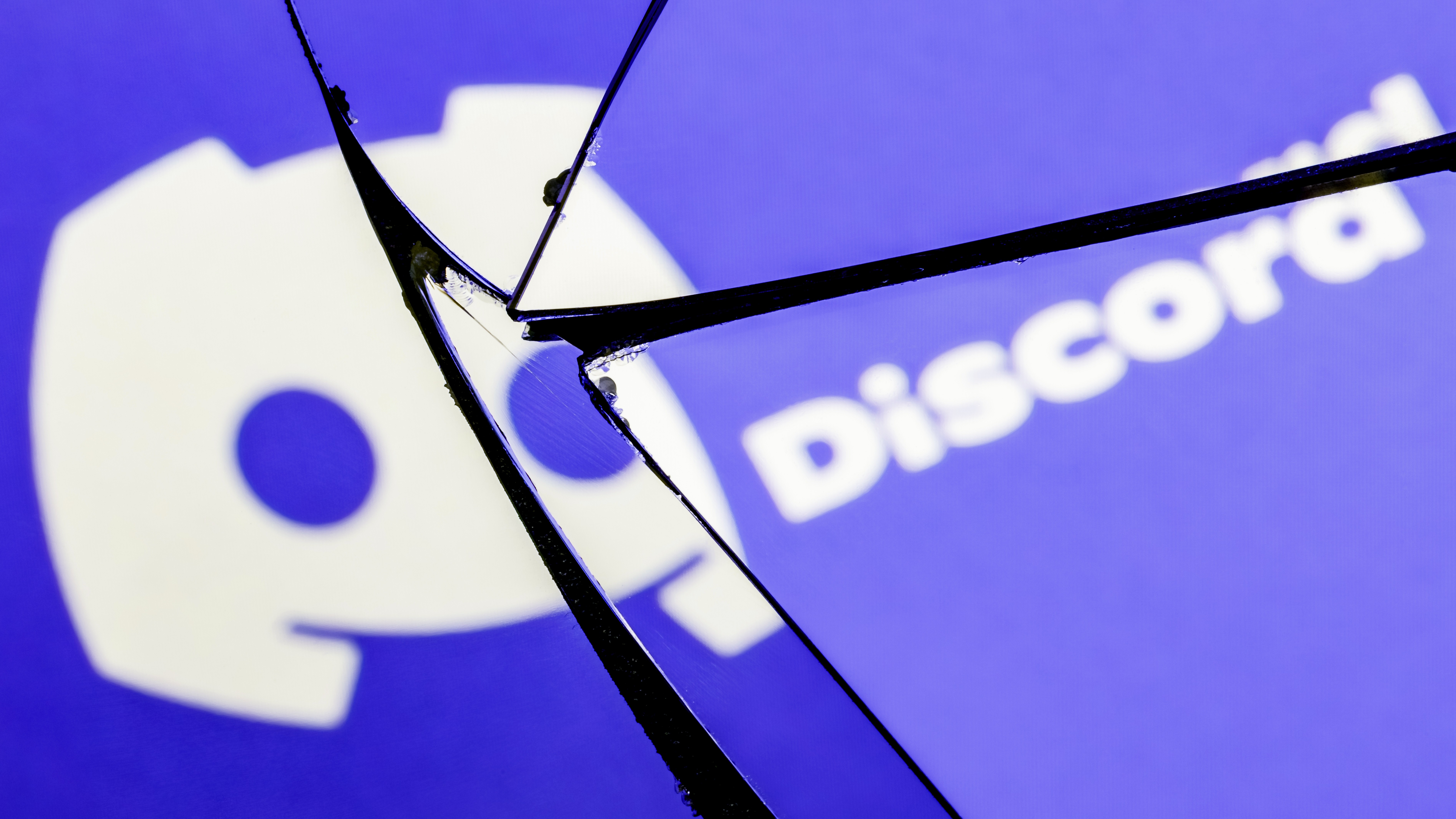 The Discord logo shown on a broken glass screen.