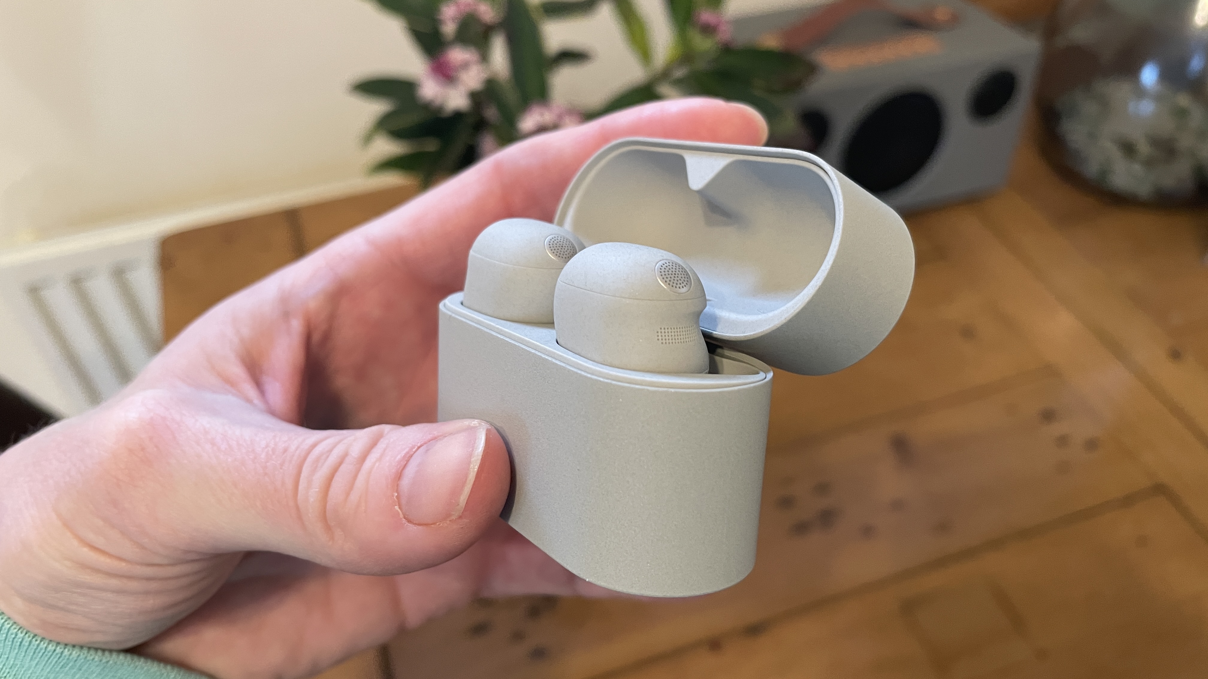 Sony WF-1000XM6 earphones next to the older generation. WF-1000XM5 and WF-C710N, on colorful table