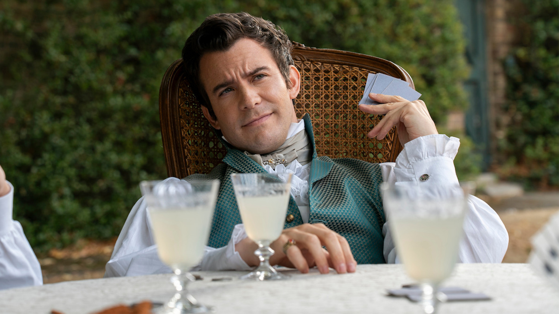 Benedict Bridgerton holds playing cards with lemonade in front of him