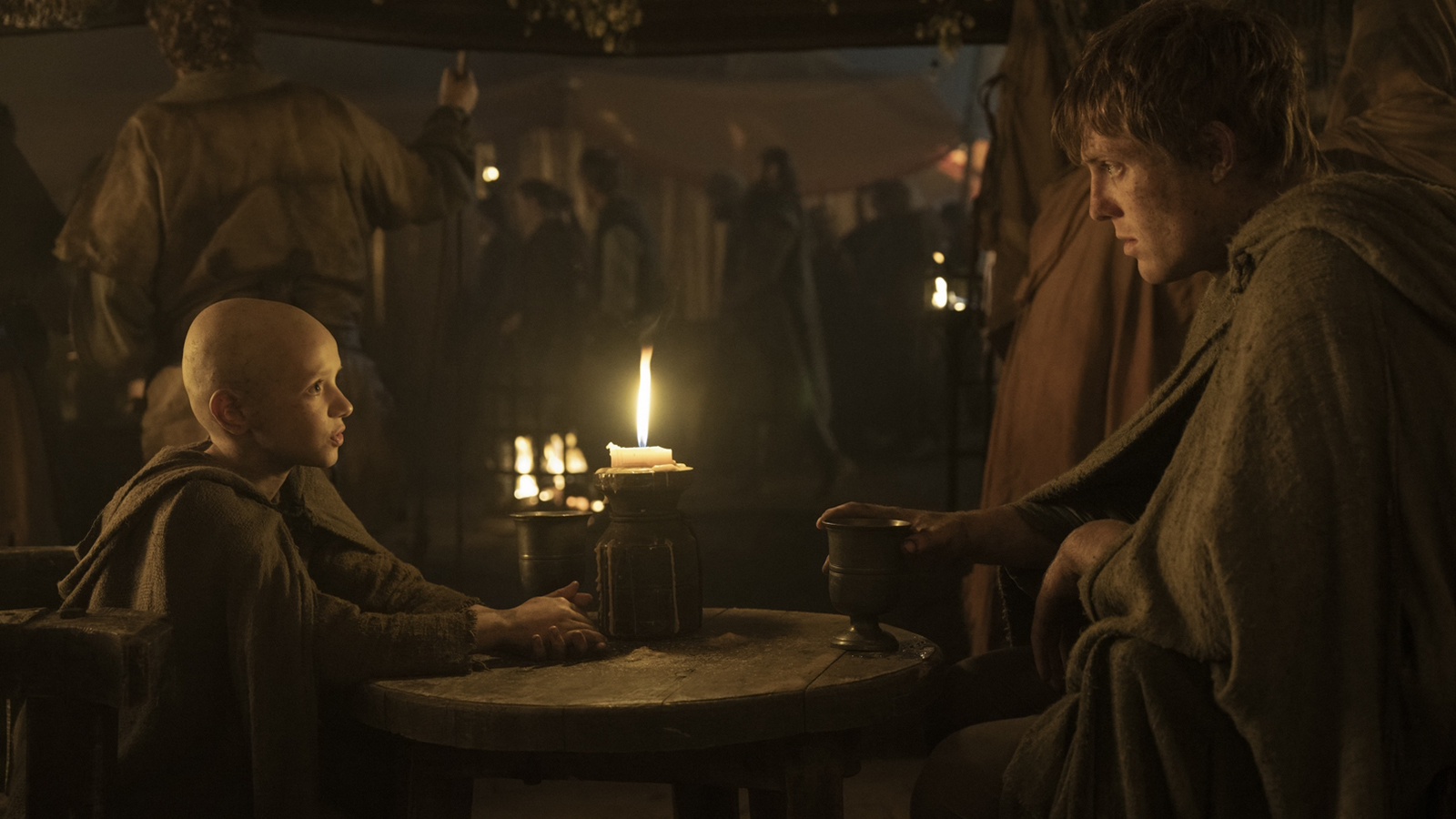 Egg and Dunk sit at a table in a candlelit tent in A Knight of the Seven Kingdoms