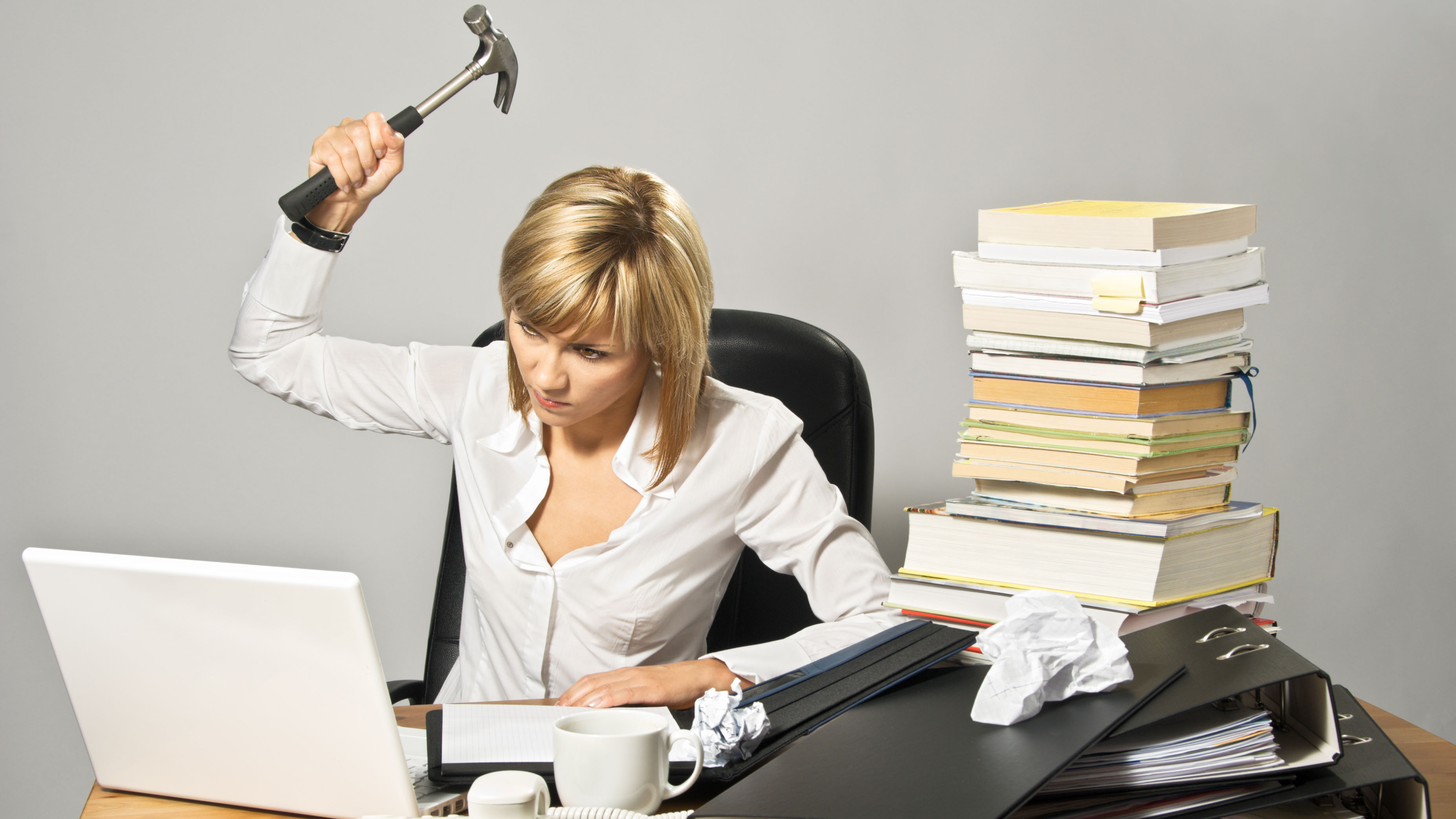 Angry businesswoman hits a laptop with a hammer.