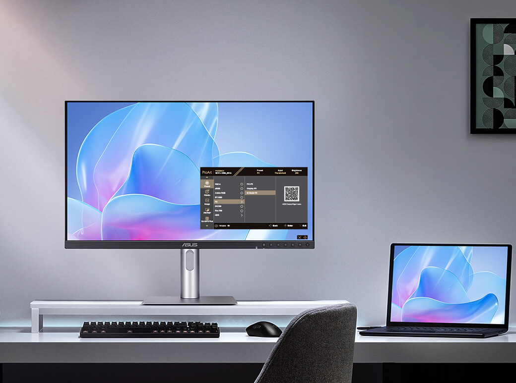 The Asus ProArt PA27JCV monitor sits on a desk next to a laptop