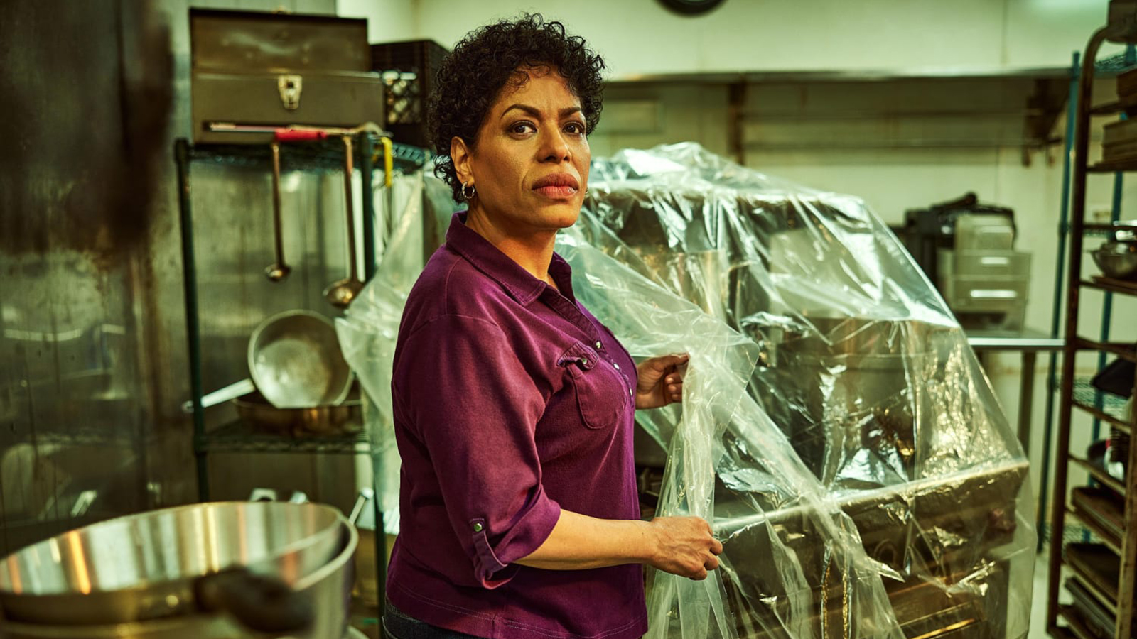 Tina is standing in a restaurant kitchen in The Bear