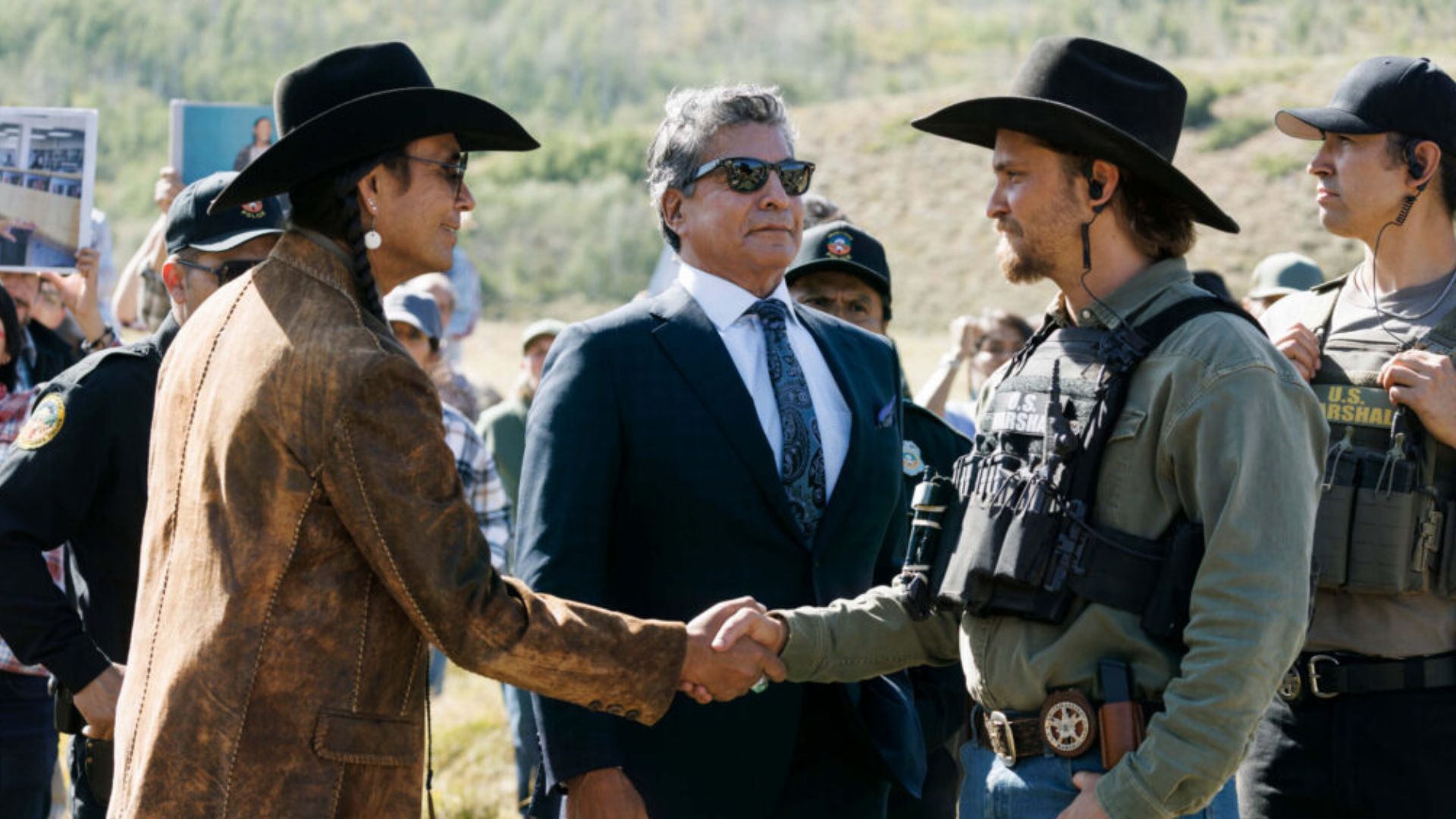 Luke Grimes shakes hands with Mo Brings Plenty