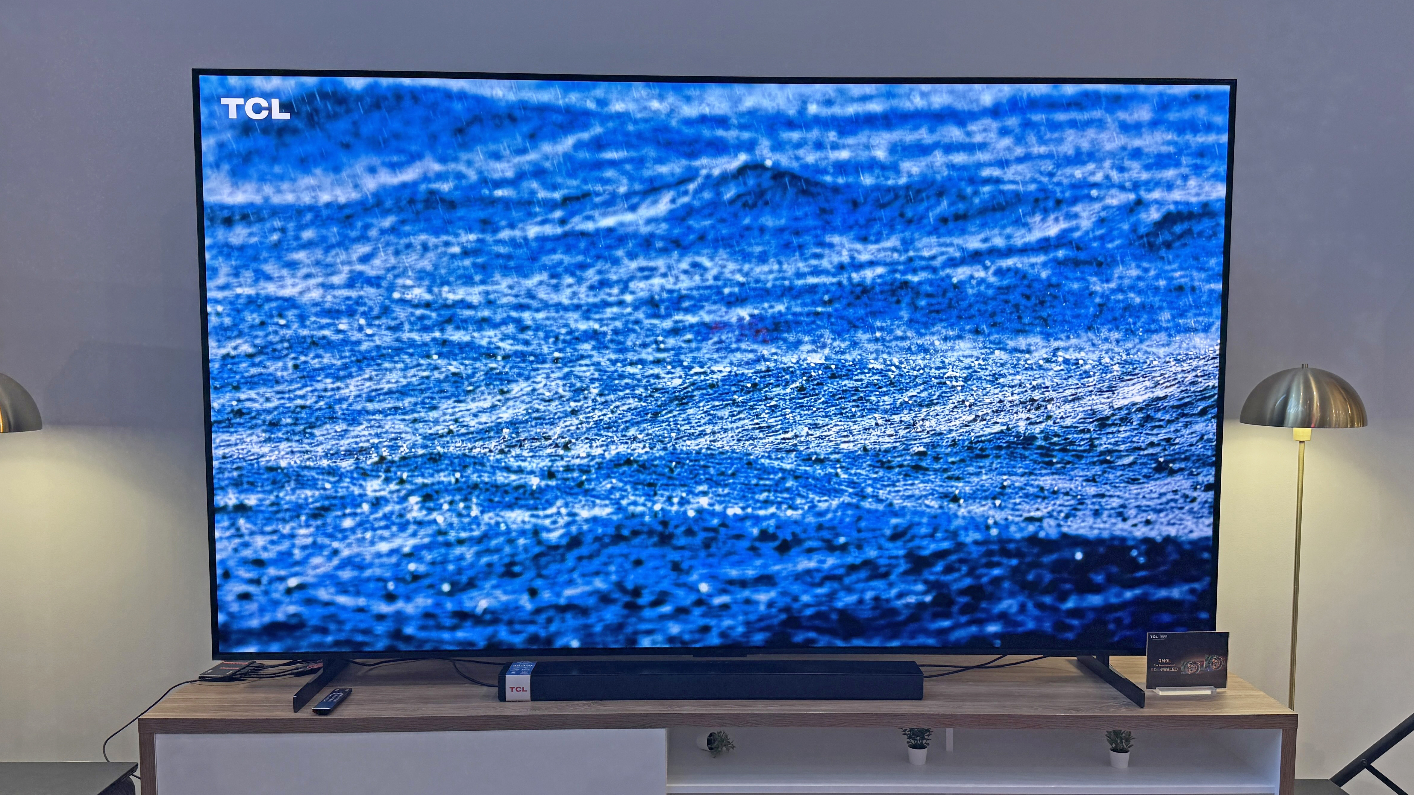 TCL RM9L TV at a launch event showing an image of rain falling on the sea, with a striking blue tone and plenty of detail in the raindrops