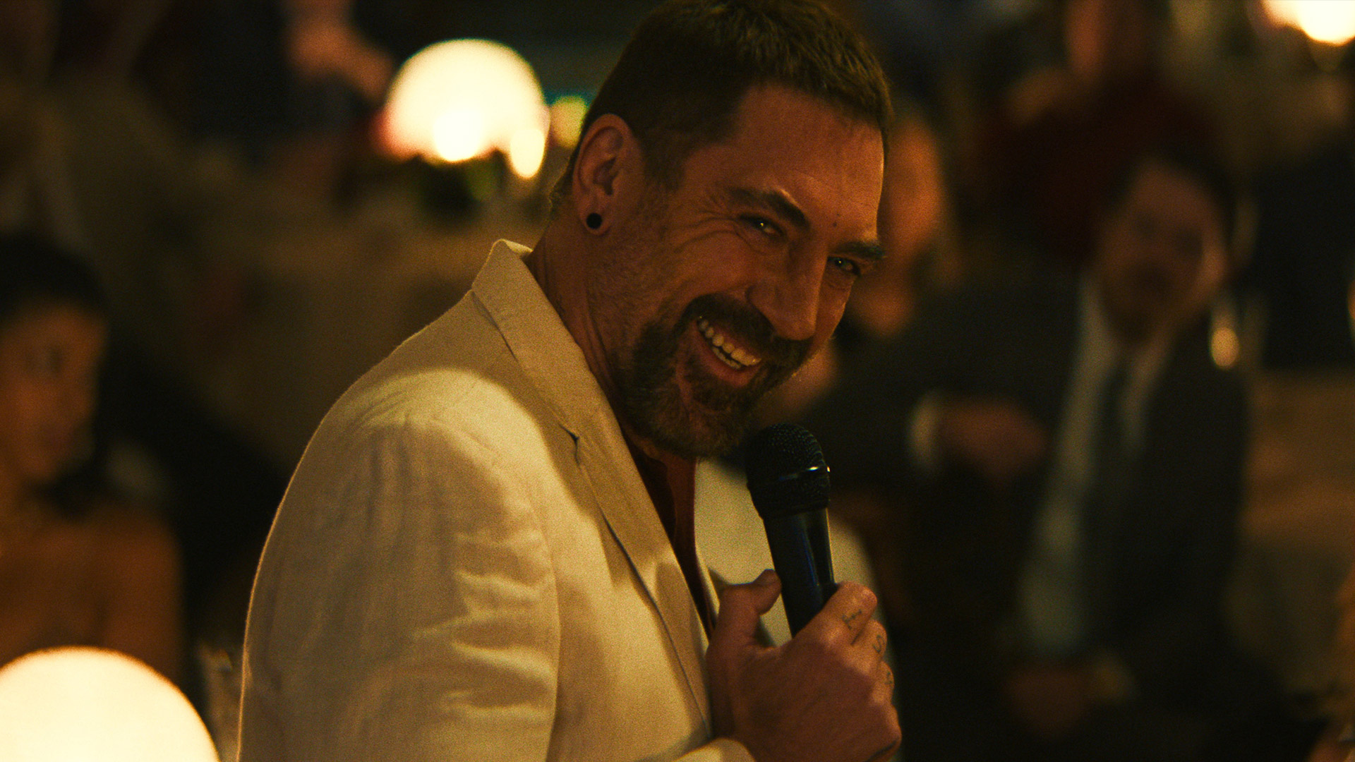 Javier Bardem laughs while holding a microphone as Max Cady in Apple TV's Cape Fear remake