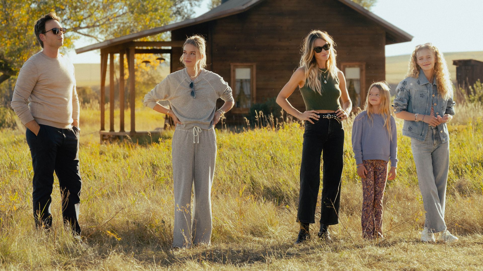 A row of people stand in a field with their hands on their hips